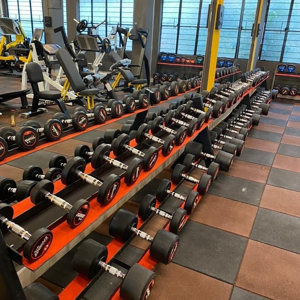 Long racks of rubber hex dumbbells over red and black rubber flooring